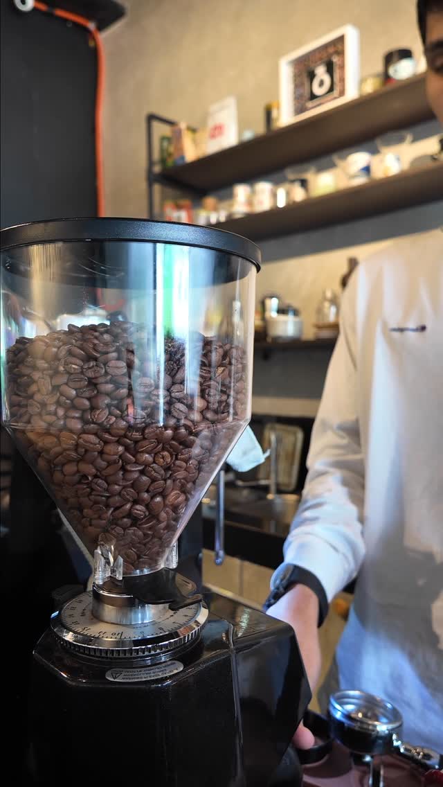 Espresso grinder and barista at work behind the Kōhī Kurabu bar